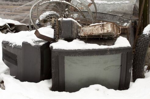 pile of old televisions laying outside in snow to be picked up by junk removal service